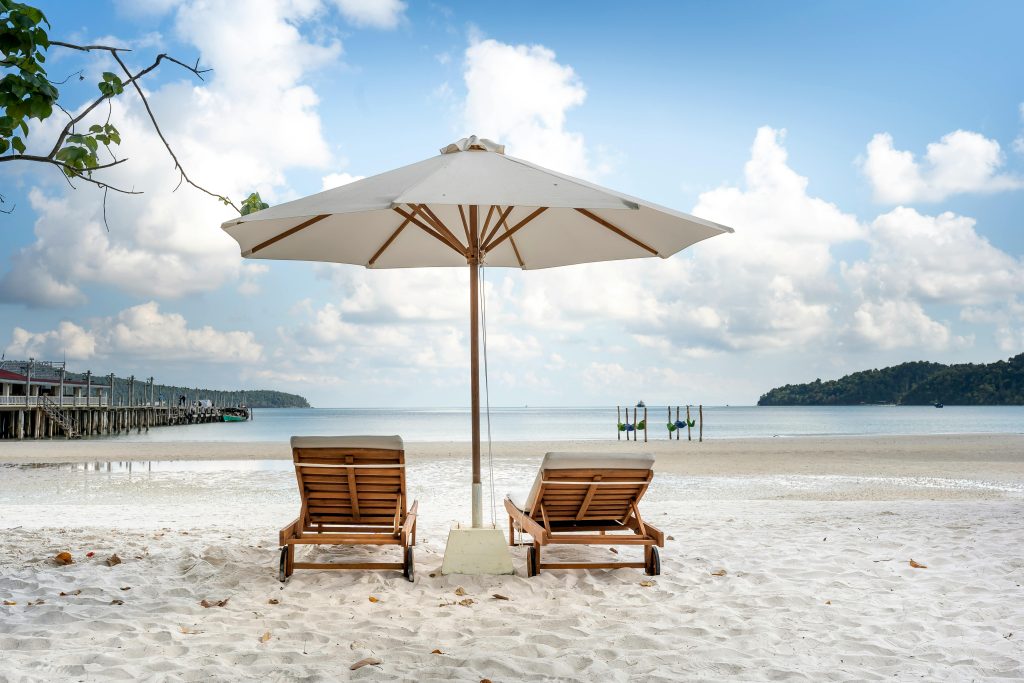 Beach scene with two empty lounge chairs under a large umbrella, representing the misuse of employee leave laws for vacation purposes.