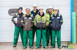 Diverse group of workers in safety gear standing together in a clean workplace.