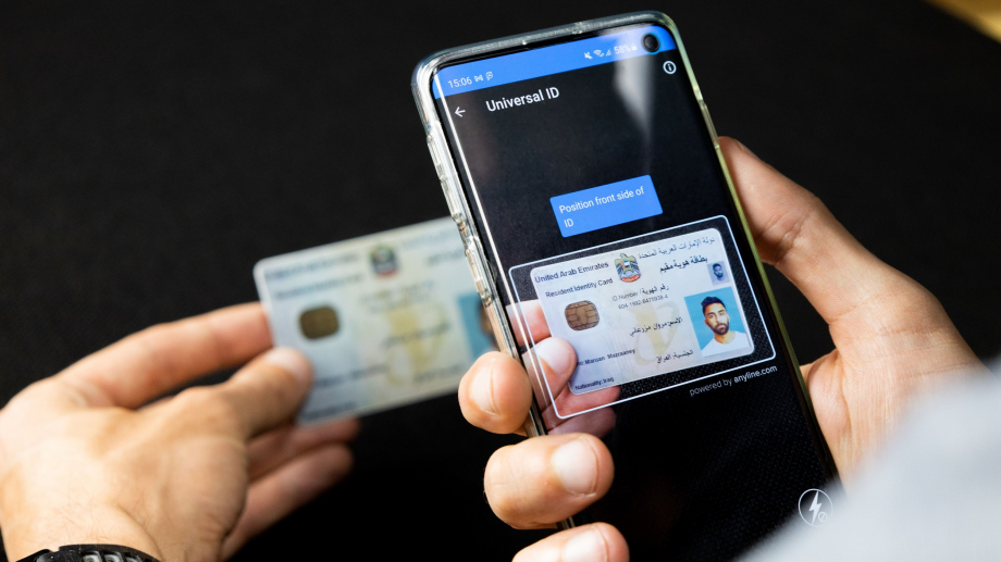 Close-up of hands scanning an ID card with verification software on a phone.